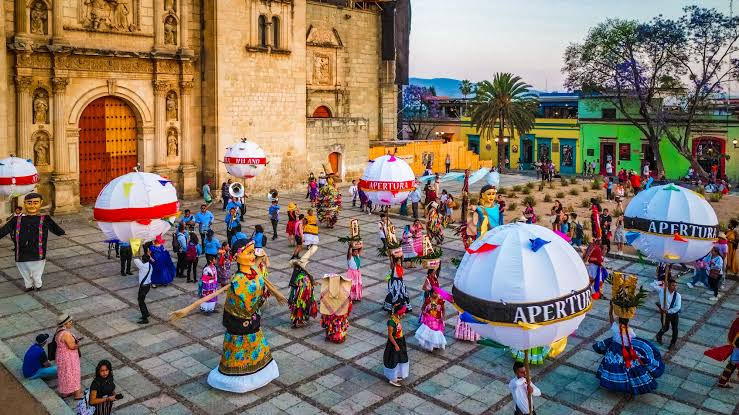 Giant papier-mâché puppets and brass band in a Oaxacan calenda at night