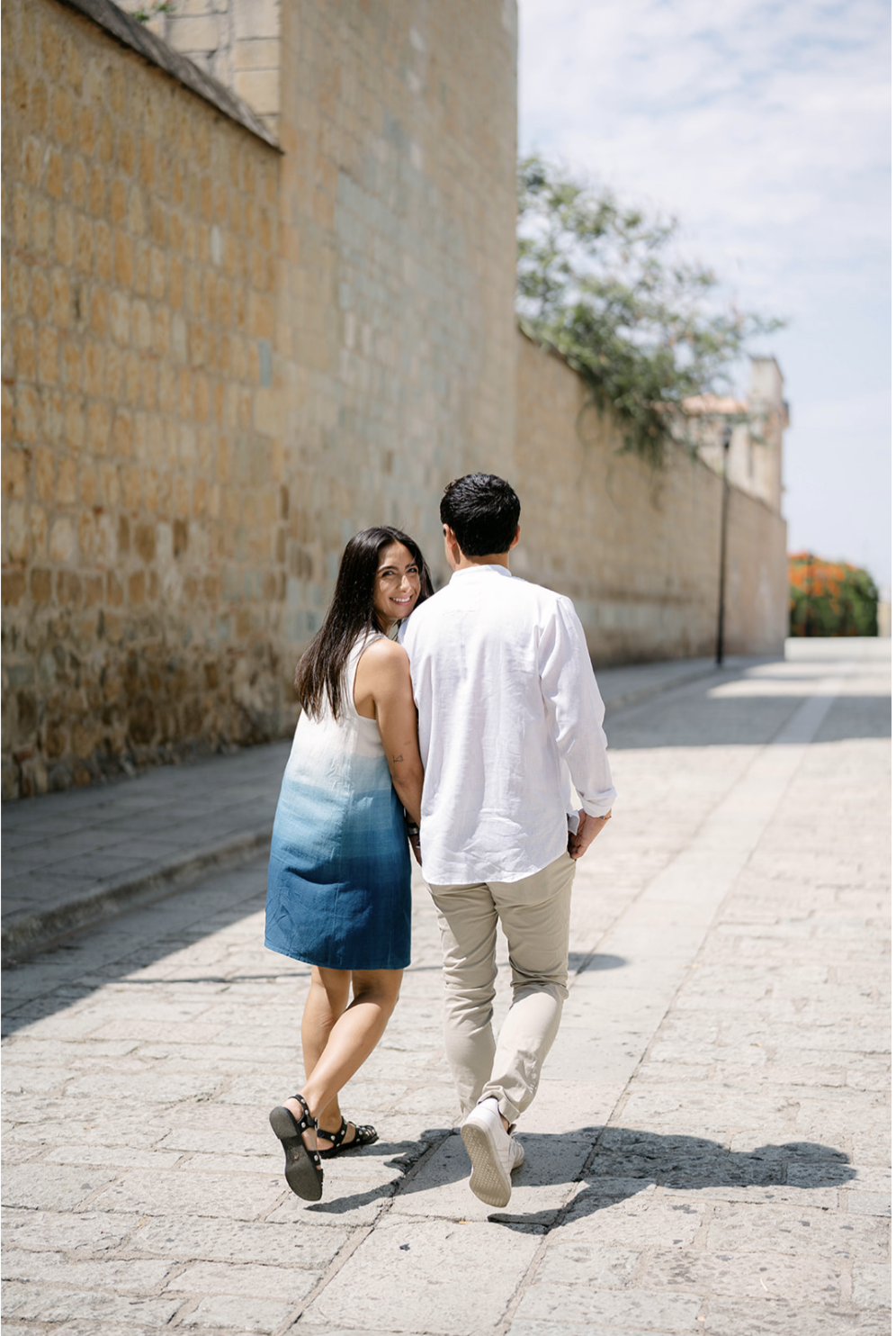 Ximena and Alexei walking together down a stone path in Oaxaca