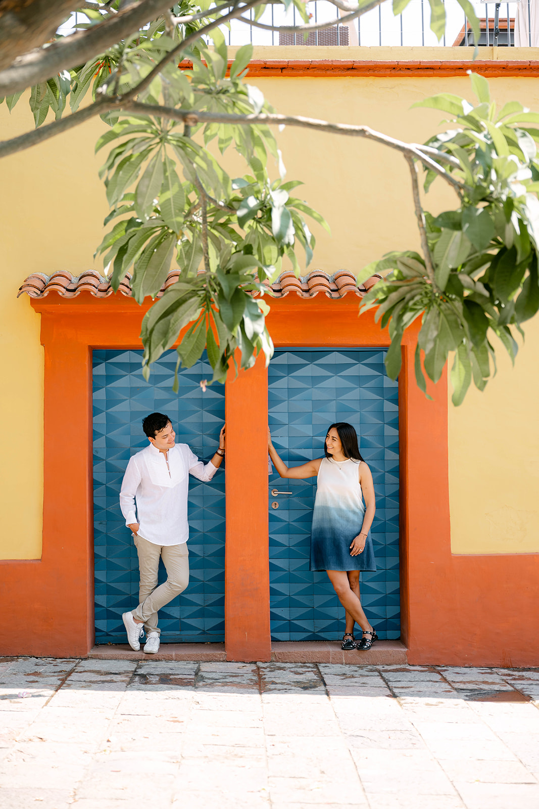 Ximena and Alexei standing in neighboring blue doorways in Oaxaca